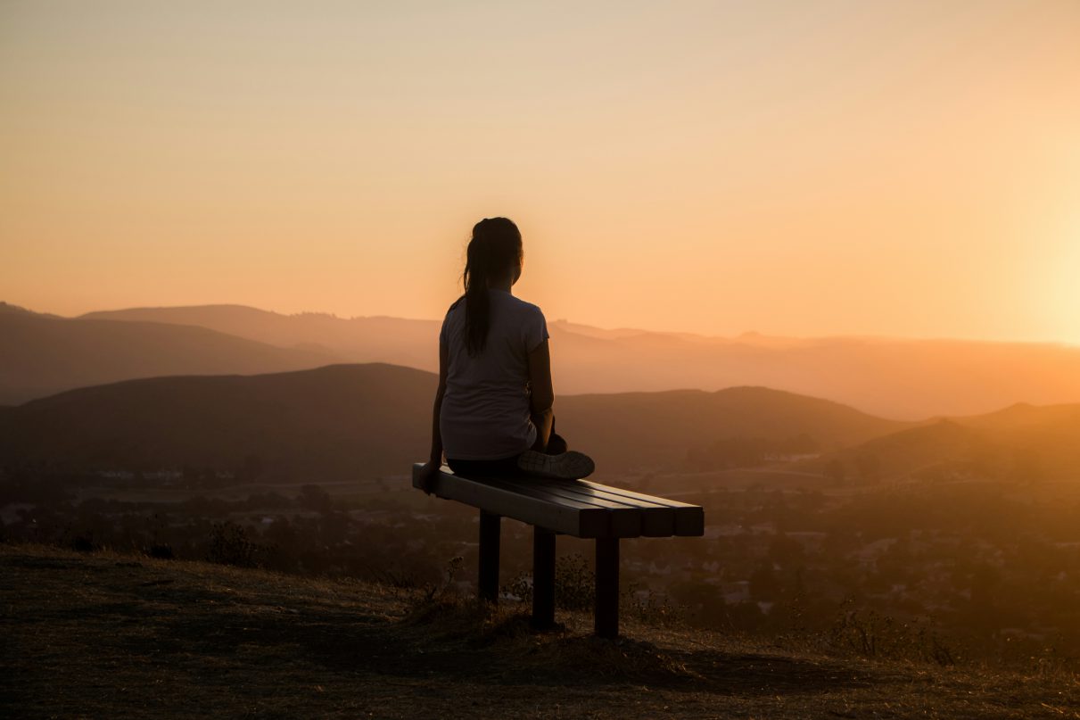 Woman sat on a bench reflecting on the world around her.