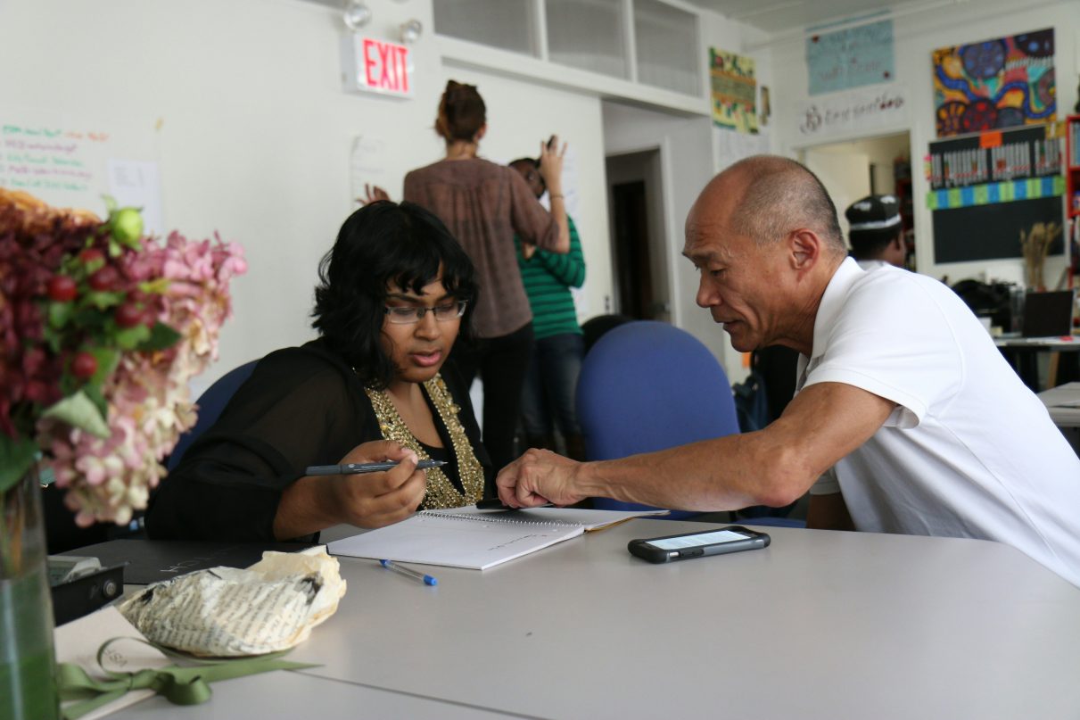 two people sat at a desk, one of them is clearly mentoring the other.